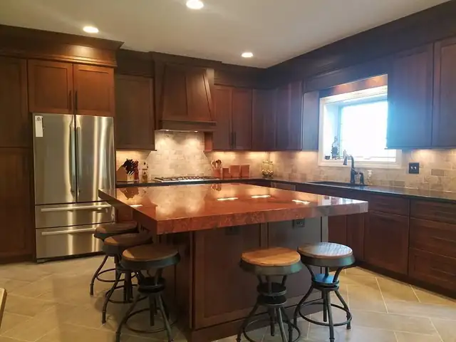 Kitchen with cherry-stained custom cabinets, tile backsplash and an island with a butcher-block top and stools